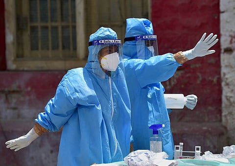 Medics wearing a PPE prepare to collect samples for COVID-19 tests at Kalasipalya police station in Bengaluru Tuesday June 23 2020. (Photo | PTI)