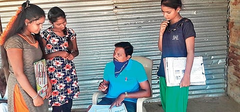 Swamy S M teaches a group of students outside a closed shop in Chitradurga