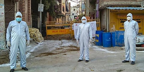 Police personnel wearing protective suits stand guard at a COVID-19 containment zone in South Delhi. (Photo | PTI)