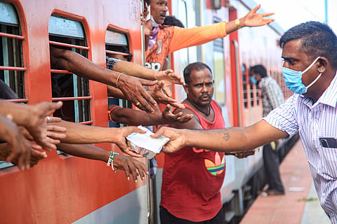 A volunteer distributes food to migrants traveling by train to their native places during the ongoing COVID-19 nationwide lockdown in Kanyakumari district Wednesday June 3 2020. (Photo | PTI)