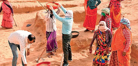 Ramavatar Singh (in blue shirt) helps a woman take away sand dug out from an MGNREGA work site