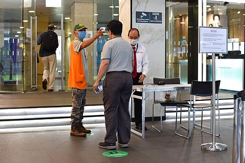 A man wearing a face mask uses a thermal scanner to check on the temperature of an individual before he can enter a building in Singapore Tuesday, June 2, 2020. (Photo | AP)