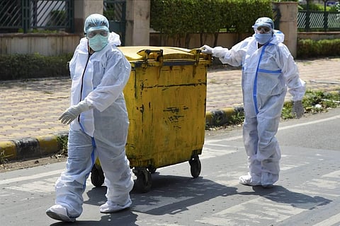Workers in protective suits dispose COVID-19 bio-medical waste outside a hospital during the ongoing nationwide lockdown to curb the spread of coronavirus in New Delhi. (Photo | PTI)