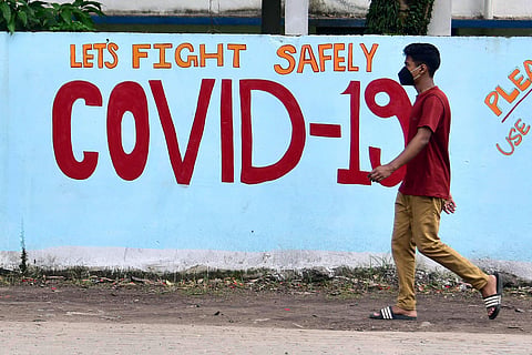 A boy passes by a COVID-19 graffiti . (Photo| ANI)
