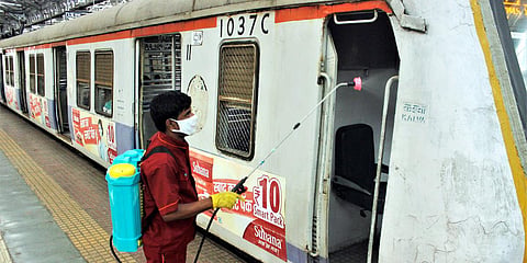 A worker sprays disinfectant to sanitize the motor man's cabin of a local train, at Chhatrapati Shivaji Maharaj Terminus in Mumbai. (File photo| ANI)