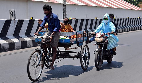 A motorist wearing PPE kit leveraging a tricycle at Periyamet. (Photo |  R Satish Babu, EPS)
