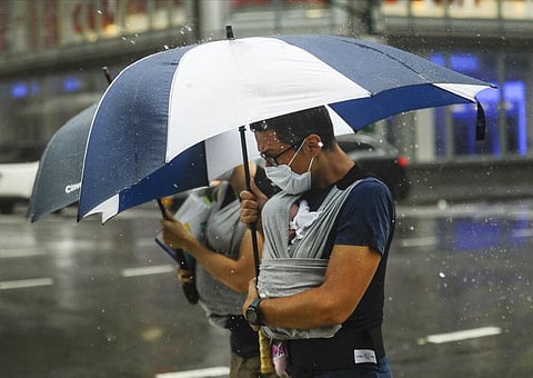 A man uses an umbrella to protect a baby from inclement weather brought about by Tropical Storm Fay, Friday, July 10, 2020, in New York. (Photo | AP)