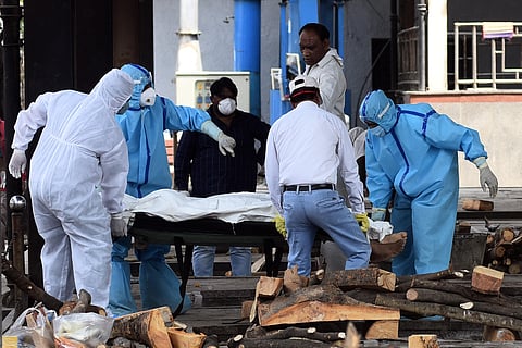 Health workers and family members in personal protective suits move the body of a man who died of COVID-19 for cremation. (File Photo | Parveen Negi, EPS)