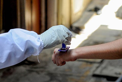 A health worker marks the hands of residents with home quarantine stamp. (Representational Photo | PTI)