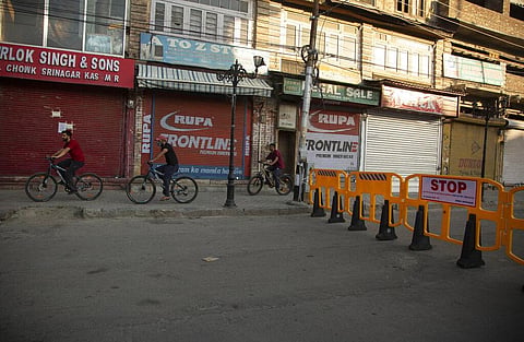 Kashmiri men ride their bicycles past fresh barricades erected by police as part of measures to stop the spread of COVID-19 in Srinagar, Sunday, July 12, 2020. (Photo | AP)