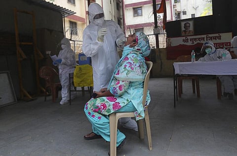 A health worker takes a swab test of a woman during a free medical checkup in Dharavi, one of Asia's biggest slums, in Mumbai. (File Photo | AP)