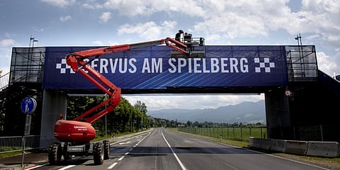 Workers install a banner reading 'Welcome to Spielberg' near the entrance to the Red Bull Ring in Austria. (Photo| AFP)