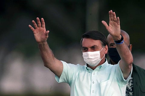 Brazil's President Jair Bolsonaro, who is infected with COVID-19, wears a protective face mask as he greets supporters  (Photo | AP)