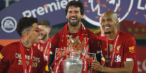 Liverpool's Roberto Firmino, left, Liverpool's goalkeeper Alisson, center, and Liverpool's Fabinho, celebrate with the English Premier League trophy. (Photo | AP)