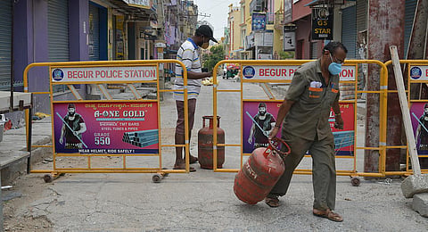 A gas agency employee delivers cylinders to residents of a containment  zone near Begur, in Bengaluru. (Photo | Meghana Sastry, EPS)