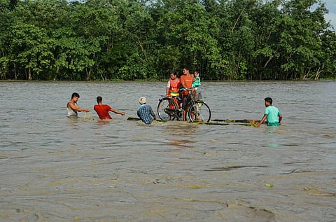 Villagers on a banana raft move to a safer place from the flooded area of Goalbil in Baksa district of Assam. (Photo | PTI)
