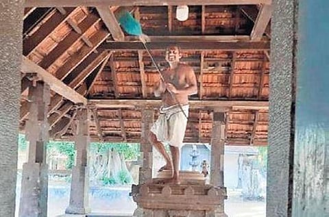 Prakash cleaning the temple roof standing on the sacred altar