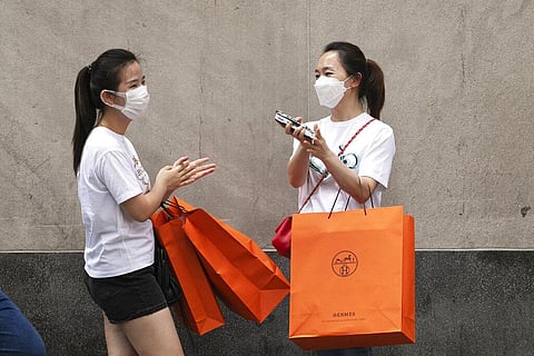 Women carrying Hermes shopping bags use hand sanitizer as they walk on Wall Street, Thursday, July 30, 2020, in New York. (Photo | AP)