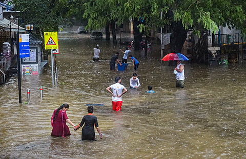 Commuters wade through a water-logged street following heavy rains in Mumbai Saturday July 4 2020. (Photo | PTI)