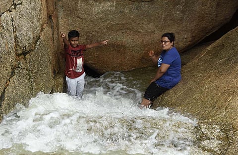 Visitors enjoying the water gushing on the steps of the historic rockfort in Chitradurga on Friday. (Photo | EPS)
