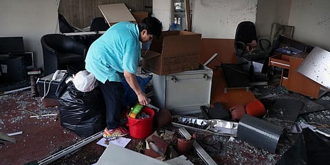 A woman carries her belongings as she leaves her damaged house, Monday, Aug. 10, 2020, in Beirut, Lebanon, near the site of last week's explosion that hit the city's seaport. (Photo | AP)