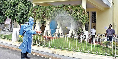 A worker sanitises the headquarters of Mysuru Urban Development Authority. (Photo | EPS)