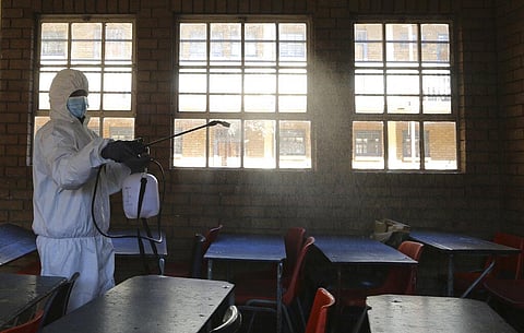 A worker from Bidvest Prestige wearing personal protective equipment, sprays disinfectant in a classroom to help reduce the spread the coronavirus in Johannesburg, South Africa. (Photo | AP)