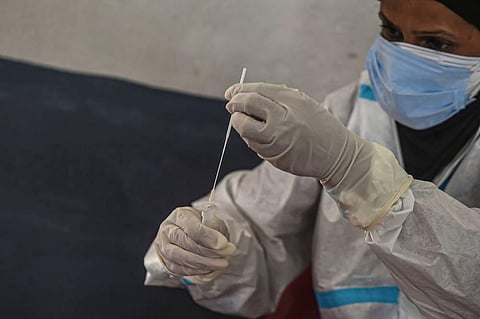 A health worker wearing a PPE kit collects a sample for COVID-19 Rapid Antigen test at Kursoo Rajbagh in Srinagar Friday. (Photo | PTI)
