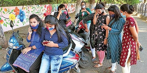 Students browsing mobile phones for their results in Bhubaneswar. (Photo | Irfana, EPS)