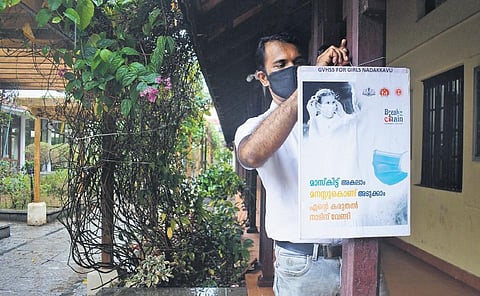 CA staffer of Nadakkavu VHSS in Kozhikode hangs a board to remind thestudents of the need to follow Covid protocol | Manu R Mavelil