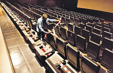 A worker sticking tape on alternate seats inside Padma theatre in Kochi so as to ensure social distancing | A Sanesh