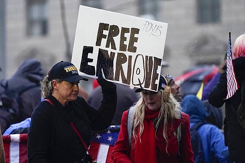 People hold a sign reading 'Free Enrique' in reference to Proud Boys leader Henry 'Enrique' Tarrio, who was arrested on Monday. (Photo | AP)
