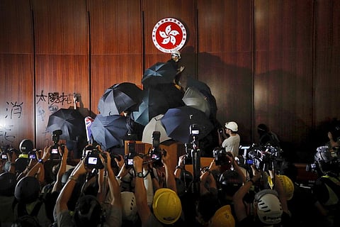 In this July 1, 2019, file photo, journalists photograph a protester defacing the Hong Kong emblem inside the meeting hall of the Legislative Council in Hong Kong.  (Photo | AP)