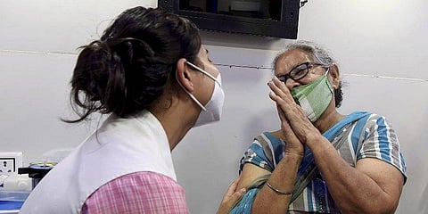A beneficiary folding hands in gratitude to a health worker before receiving a dose of Covid vaccine in New Delhi. (PTI)