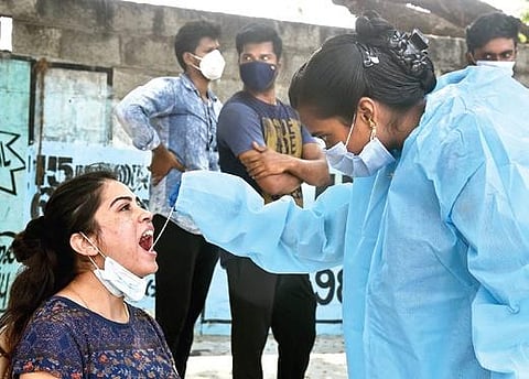 A health care worker collects a swab sample from a woman.