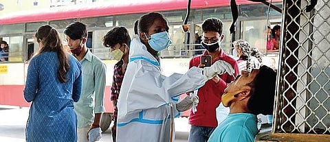 A health worker collects swab samples of a passenger at Kempegowda Bus  Station in Bengaluru on Sunday. (Photo | Shriram BN)