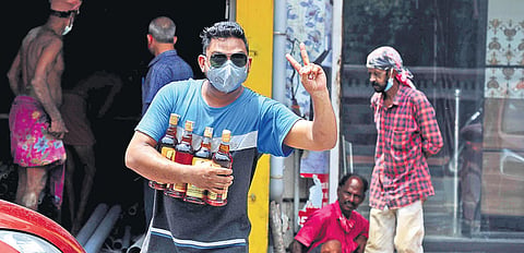An  elated consumer flashes a victory sign after managing to buy his quota of liquor from a Bevco outlet at Fort Kochi in this file photo. (EPS)
