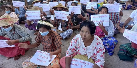 Women sit-in protest in the village of Latpantaung in Myanmar while holding signs calling for the freezing of revenues the Myanmar military gets from the sale of oil and gas. (Photo | AP)