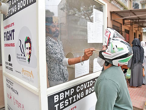 A health worker collects swab samples of a man at a PHC in Bengaluru on Friday. (Photo | Vinod Kumar T/EPS)