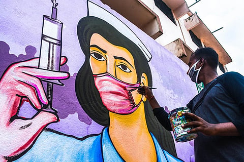 An artist busy painting on walls on the theme of COVID-19 in Bhubaneswar. (File photo| Biswanath Swain, EPS)