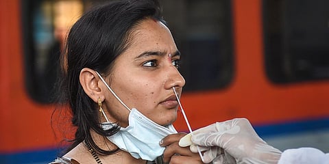 A health worker collects a swab sample of a traveler to test for COVID-19, at Dadar railway station in Mumbai. (Photo| PTI)