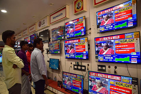 People watch Finance Minister Nirmala Sitharaman presenting Union Budget 2021-21 on television sets at an electronics store. (Photo | V Karthikalagu, EPS)