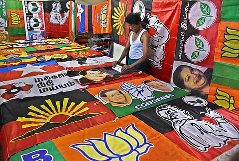 A worker displaying flags of several political parties in Coimbatore. (Photo | U Rakesh Kumar, EPS)