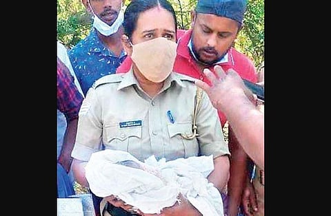 Police officials with the  newborn, who was found abandoned near Walayar