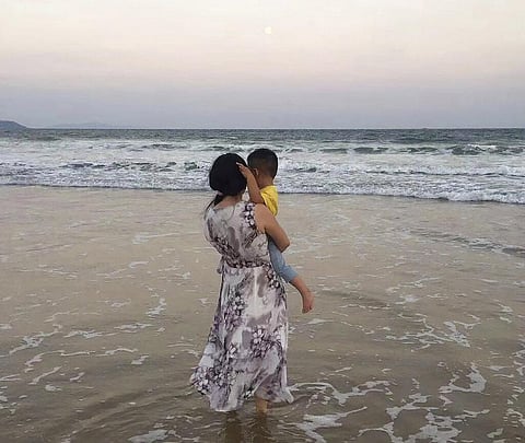 In this photo released by Zou Xiaoqi, Zou Xiaoqi, a single mother turned activist in Shanghai, holds her son as they visit a beach in Sanya, southern China's Hainan province. (Photo | AP)