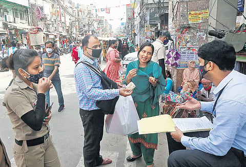 A Delhi civil defence personnel issues a challan to a woman for not wearing a face mask in New Delhi on Thursday | Shekhar Yadav