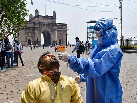 A health worker, wearing PPE kit, conducts COVID-19 test of a person at the Gateway of India in Mumbai. (Photo | PTI)