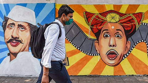 A man wearing a face mask as a precaution against Covid-19 walks past a mural at Lalbaug in Mumbai. 