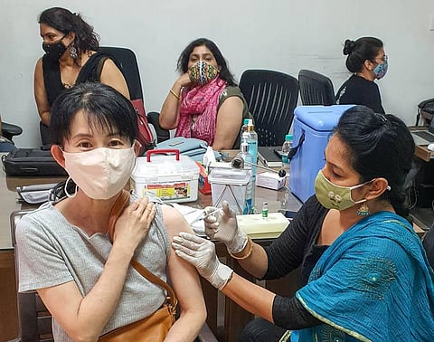 A medic administers the COVID-19 vaccine dose to a Japanese woman during a vaccination drive at IMT Industrial Association office, at Manesar in Gurugram district. (Photo | PTI)