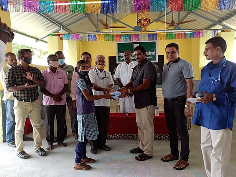 Plus Max Group of Companies Owner Prakadeesh Kumar handing over a Covid- 19 kit to a class 12 student of Poolambadi Government High School. (Photo | EPS)